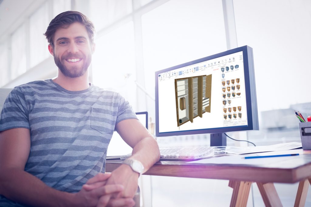 Employee smiles at the camera in front of a monitor with a closet project