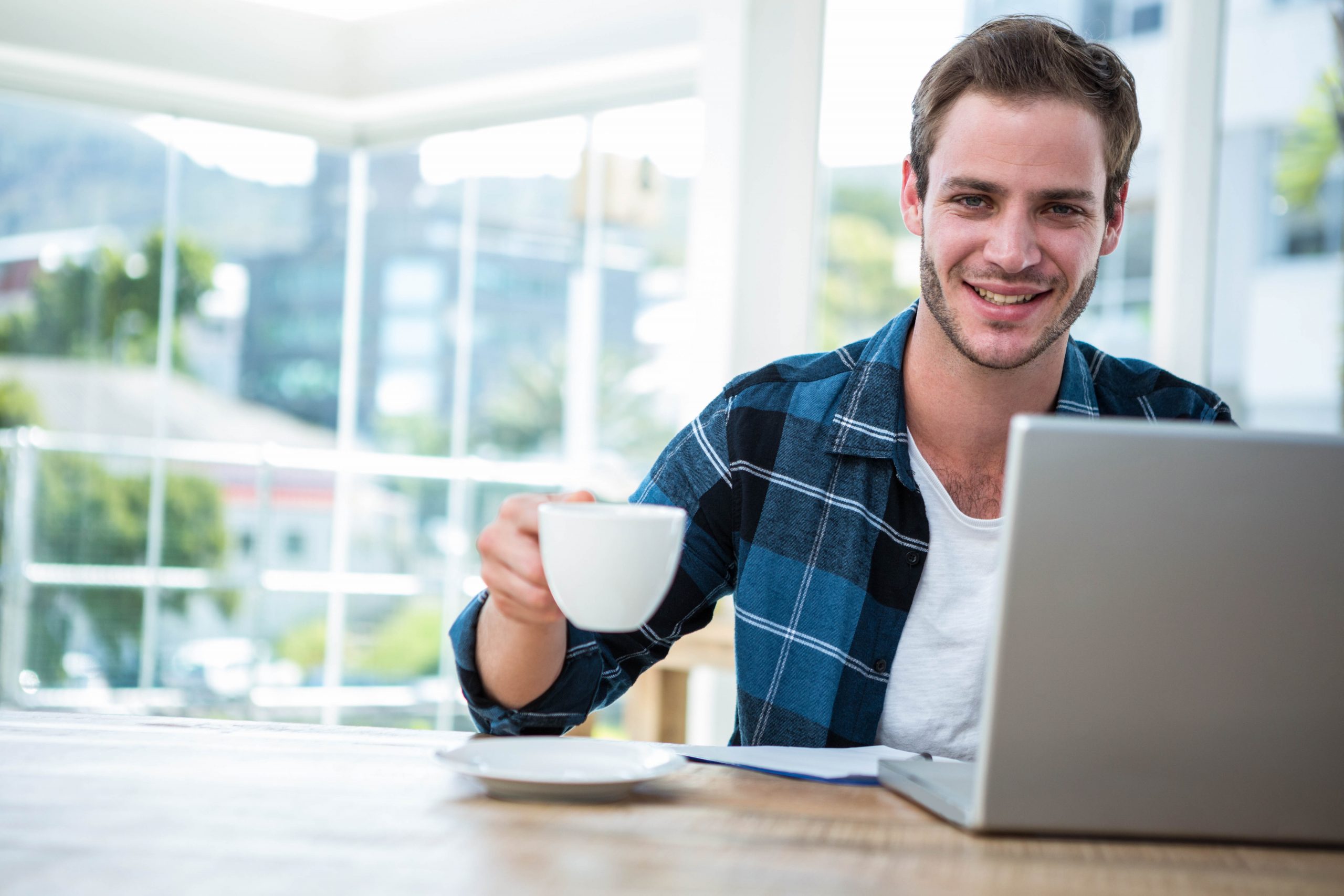 Mann mit Kaffetasse vor Notebook